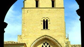 Un bâtiment historique doté d’une tour imposante, de fenêtres en arc de cercle et d’un toit recouvert de tuiles.