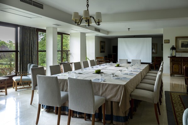 A conference room with a long table, chairs, and a projector screen. - Parador De Gijon (Gijon)