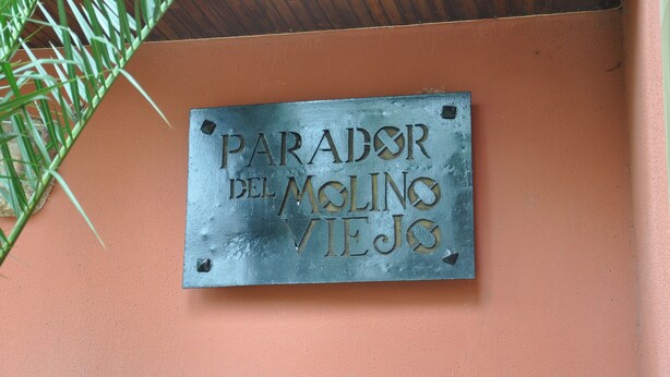 A metal plaque with the text "PARADOR DEL MOLINO VIEJO" mounted on a wall.