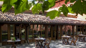 Un patio al aire libre con suelo de piedra y mesas y sillas de madera.