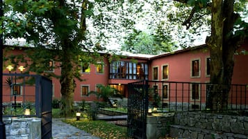 A courtyard with a stone wall, a gate, and a building with multiple windows and balconies.
