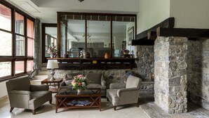 Una sala de estar acogedora con chimenea de piedra, asientos cómodos y amplios ventanales que dejan entrar la luz natural.