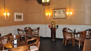 A dining area with wooden tables and chairs, wall-mounted light fixtures, and framed artwork.