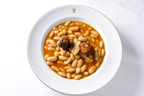 Un plato blanco con sopa de frijoles y trozos de salchicha.