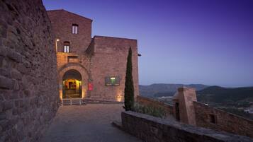 Un edificio de piedra con una entrada arqueada, un letrero que indica un restaurante y vistas del paisaje circundante.