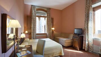 Une chambre d’hôtel avec un lit, un bureau avec une lampe, une télévision et un canapé.