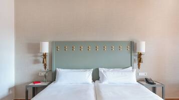 A double bed with white linens, two bedside tables with lamps, and a wall-mounted light fixture.