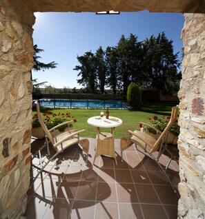 A patio with wicker chairs and a table, overlooking a pool and garden. - Parador De Benavente  (Benavente)