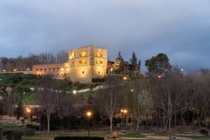 A historic building with multiple levels and arched windows, surrounded by a landscaped area with trees and pathways. - Parador De Benavente  (Benavente)