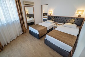 Une chambre d’hôtel avec deux lits, un miroir, une table de chevet avec une lampe et un appareil de climatisation.