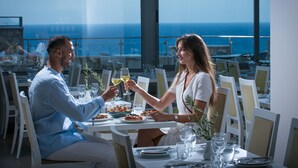 Una coppia cena a un tavolo con vista sull'oceano.