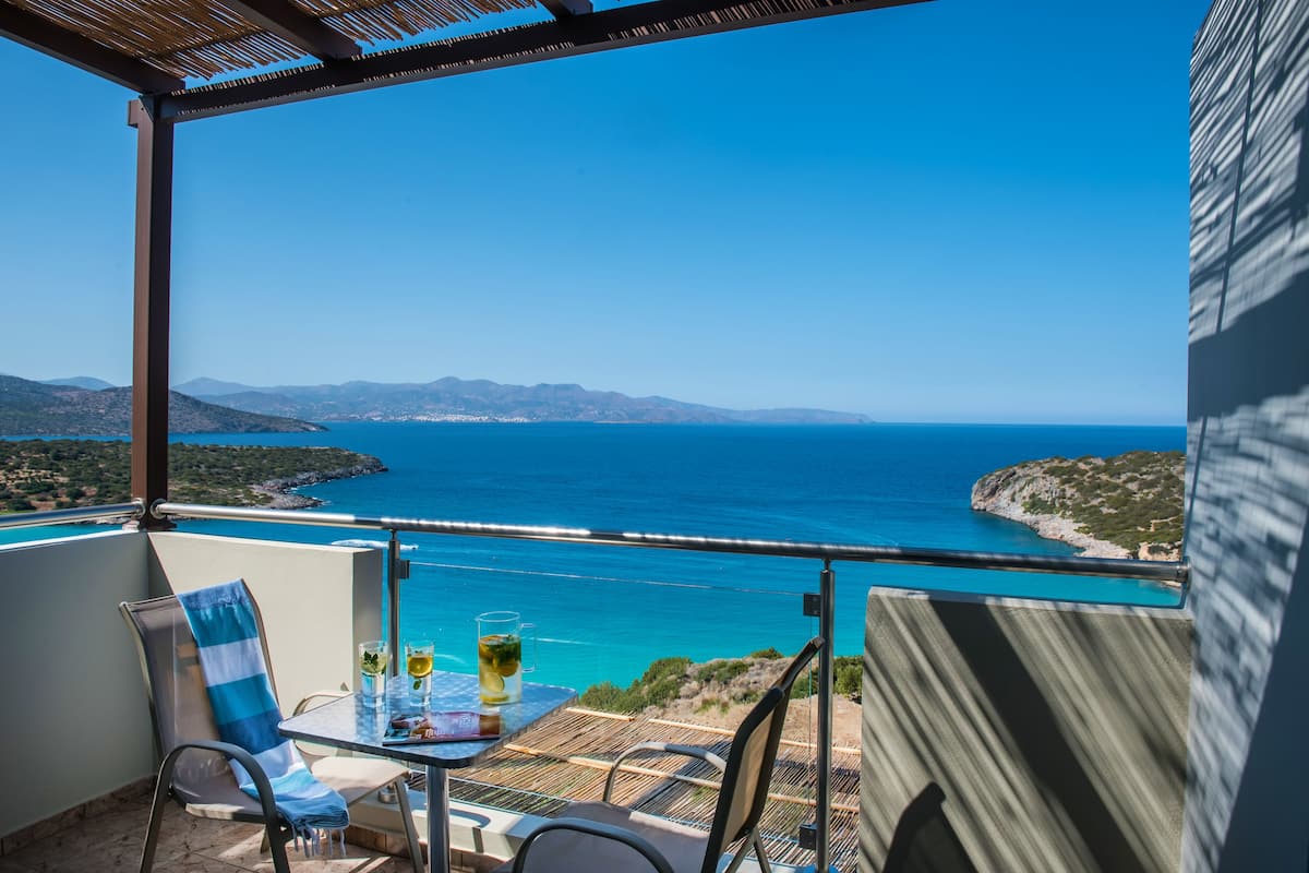 Ein Balkon mit Tisch, Stühlen und einem Glas Drink.