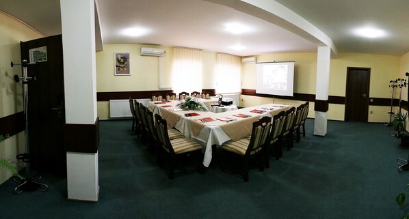 A conference room with a long table, chairs, a projector screen, and a whiteboard.