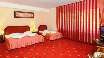 A hotel room with two beds, a television, and a red carpeted floor.