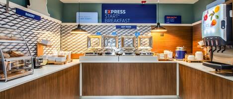 A modern breakfast area with a sign for Express Start® Breakfast, a juice dispenser, and a bakery section.