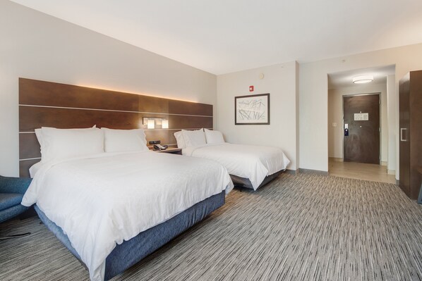 A hotel room with two beds, a large headboard, a wall-mounted light, a framed abstract artwork, and a carpeted floor. - Holiday Inn Express Hotel & Suites Orlando - Apopka by IHG (Apopka)