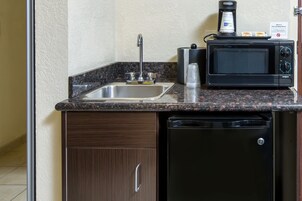 Cocina compacta con pileta de acero inoxidable, cafetera, microondas y lavavajillas.