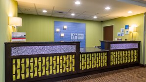 A reception desk with a Holiday Inn Express sign, a patterned floor, and a wall-mounted lamp. - Holiday Inn Express Hotel & Suites Orlando - Apopka by IHG (Apopka)
