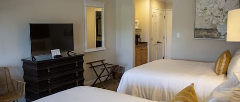 Habitación de hotel con dos camas, un aparador, un televisor y un cuadro en la pared.