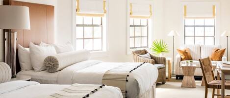 A hotel room with a large bed, a sitting area with a chair and a table, and a window with a view.