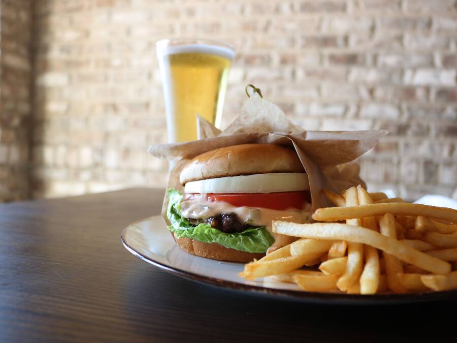 A burger with fries and a glass of beer on a table.
