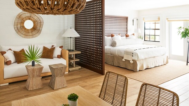 A modern bedroom with a wooden headboard, a large window, and a bedside table with a lamp. - Inn On The Lakes (Sebring)