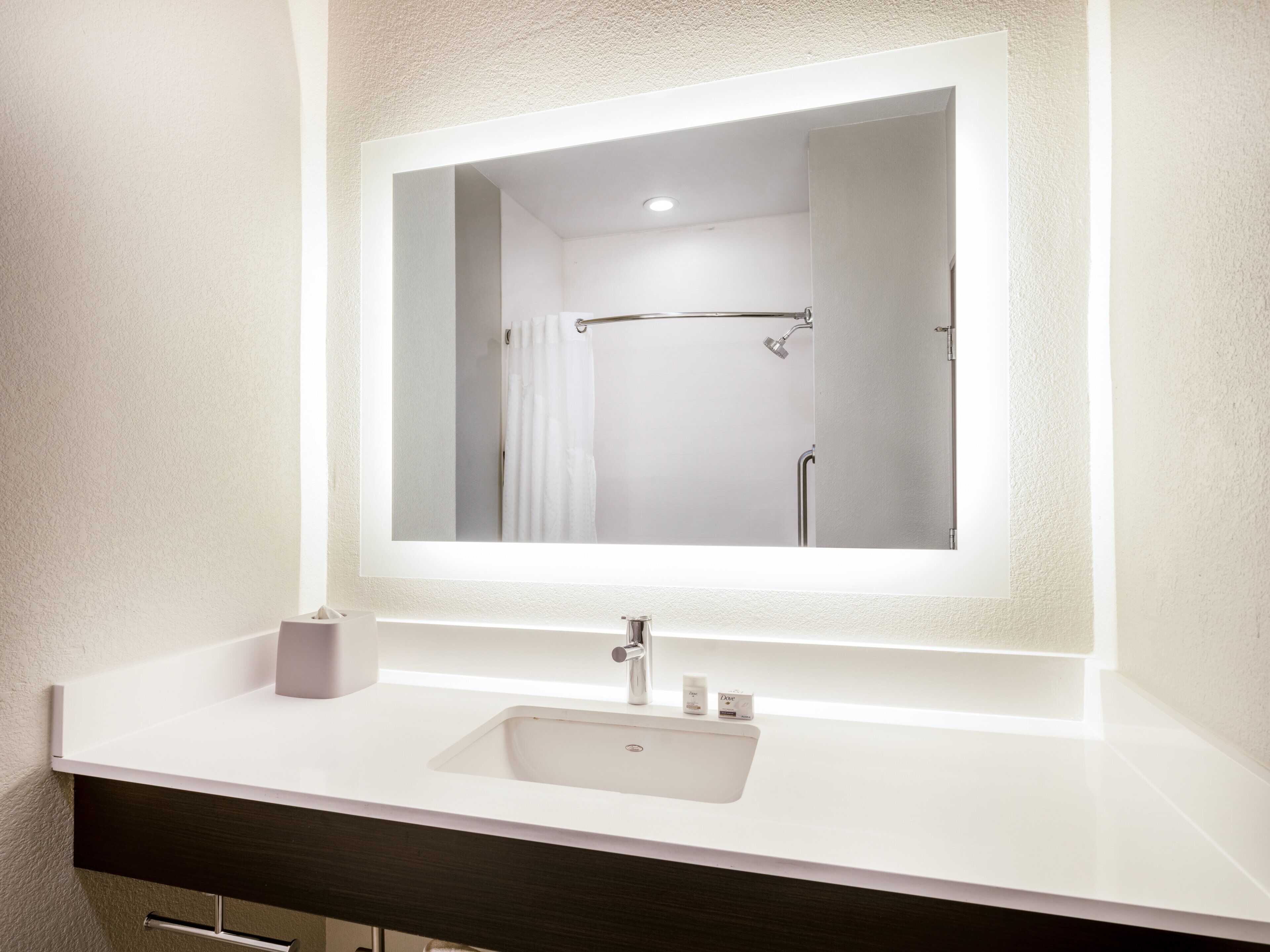 Une salle de bain avec un lavabo blanc, un miroir et un espace douche.