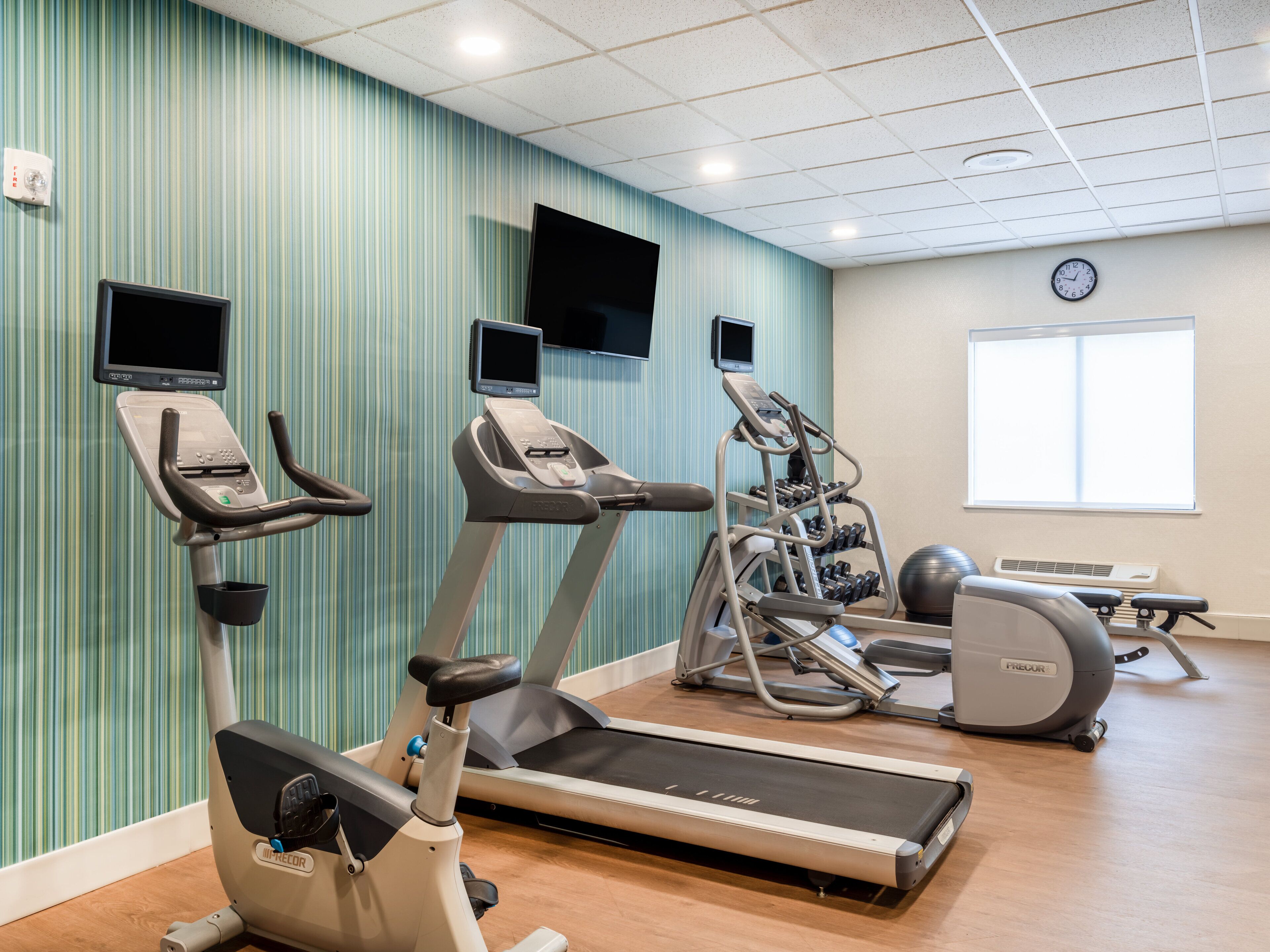 Een fitnessruimte met loopbanden, elliptische trainers en een hometrainer.