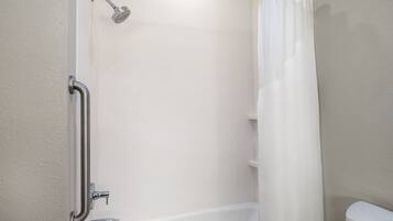 A bathroom with a shower, toilet, and grab bar.