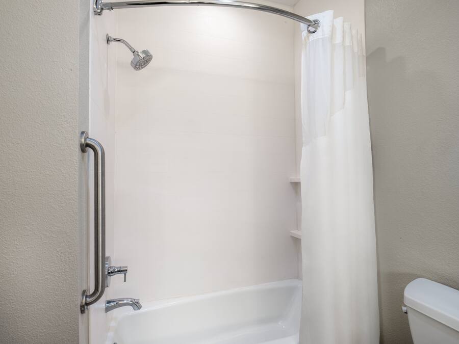 A bathroom with a shower, toilet, and grab bar.
