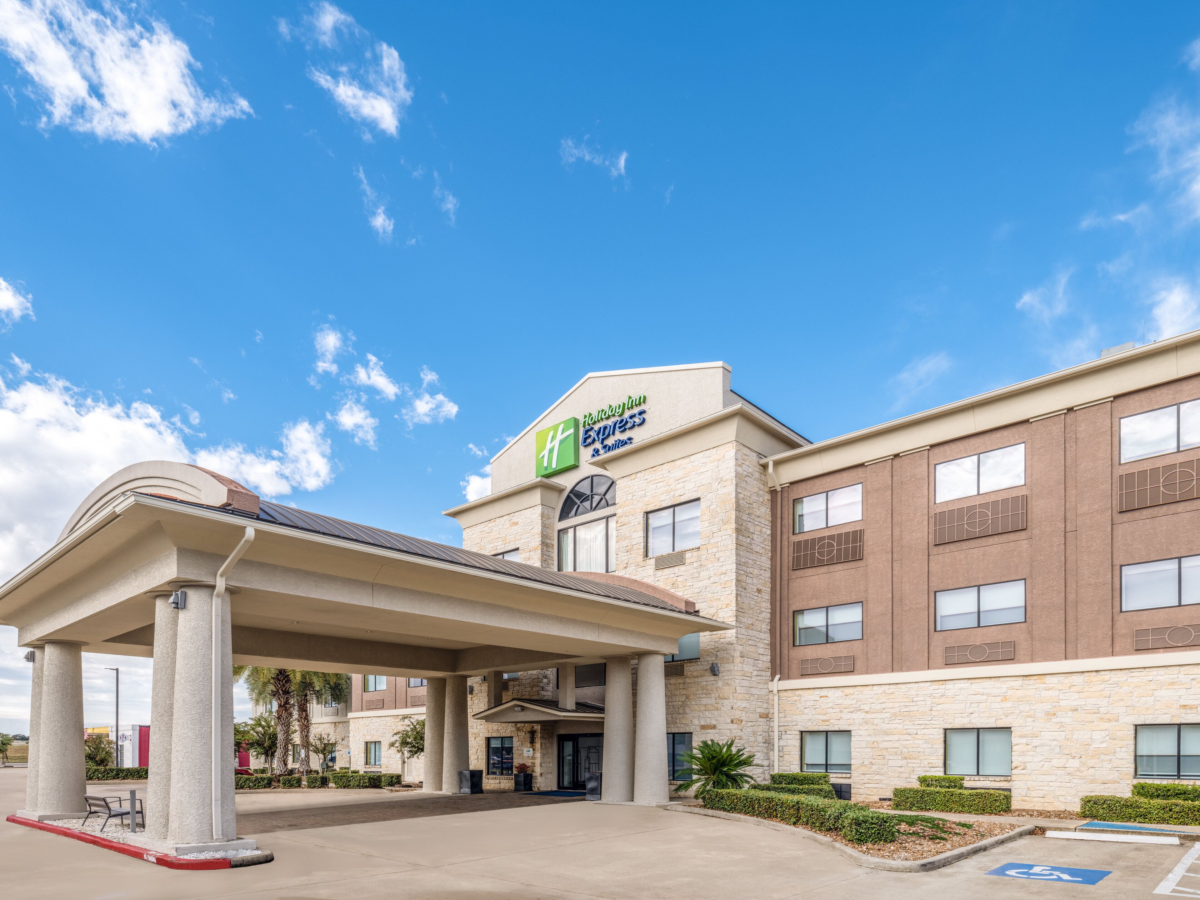 Un hôtel Holiday Inn Express doté d’une entrée couverte, d’une façade en pierre et surplombant un ciel d’un bleu éclatant.