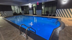 Une piscine intérieure à l’eau claire, dotée d’une échelle en métal et de panneaux d’avertissement relatifs à la sécurité.