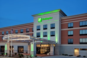 Un hotel Holiday Inn con entrada cubierta, varias ventanas y una bandera estadounidense.