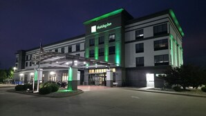 Un hôtel Holiday Inn au design moderne, doté d’une entrée couverte et arborant un drapeau américain bien visible.