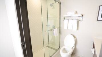 A modern bathroom with a glass-enclosed shower, a white toilet, and a towel rack with neatly folded towels.