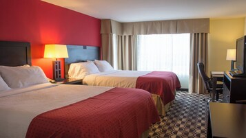 Habitación de hotel con dos camas, un escritorio con ordenador y una ventana con cortinas.