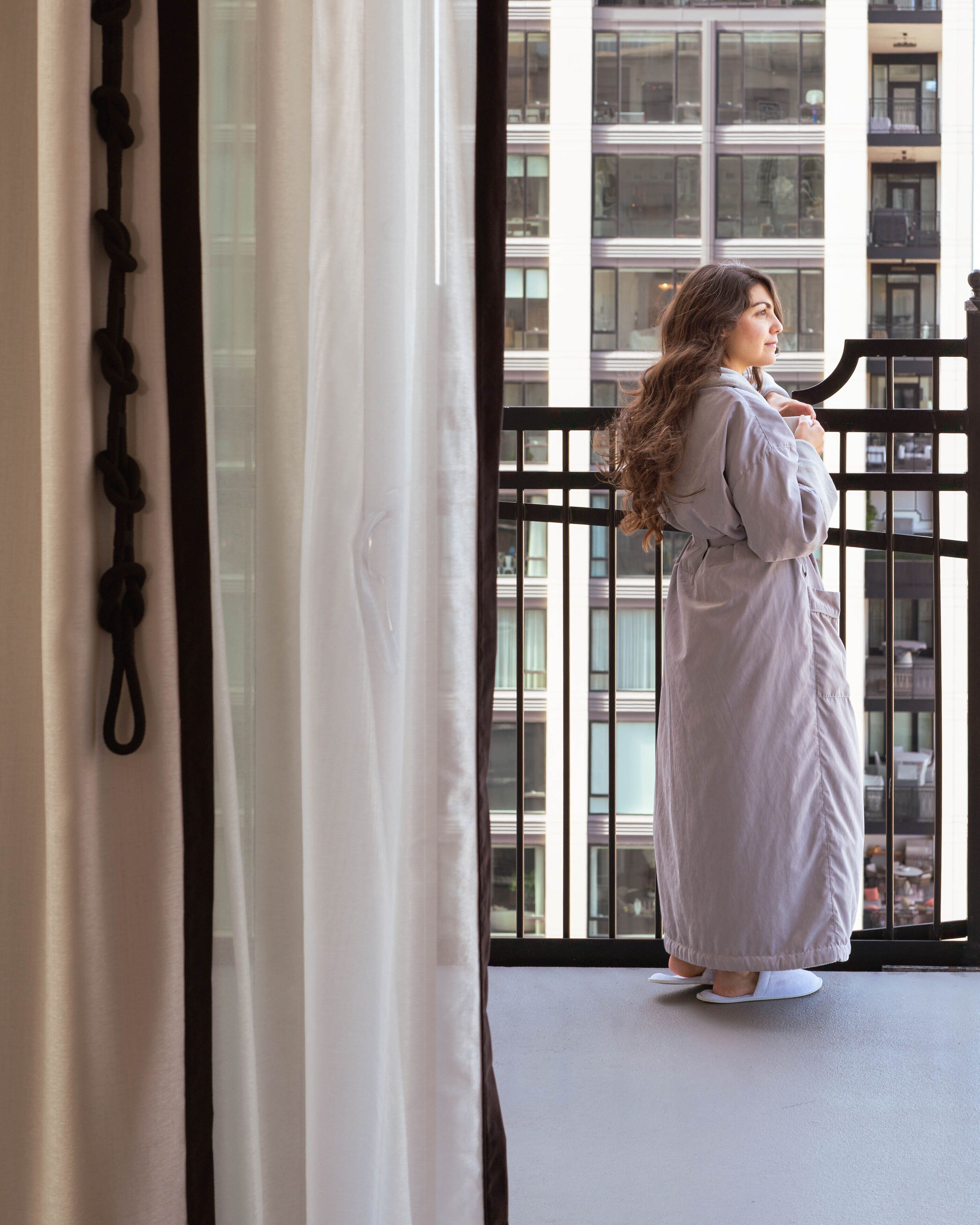 A person standing by a window with a view of a building.