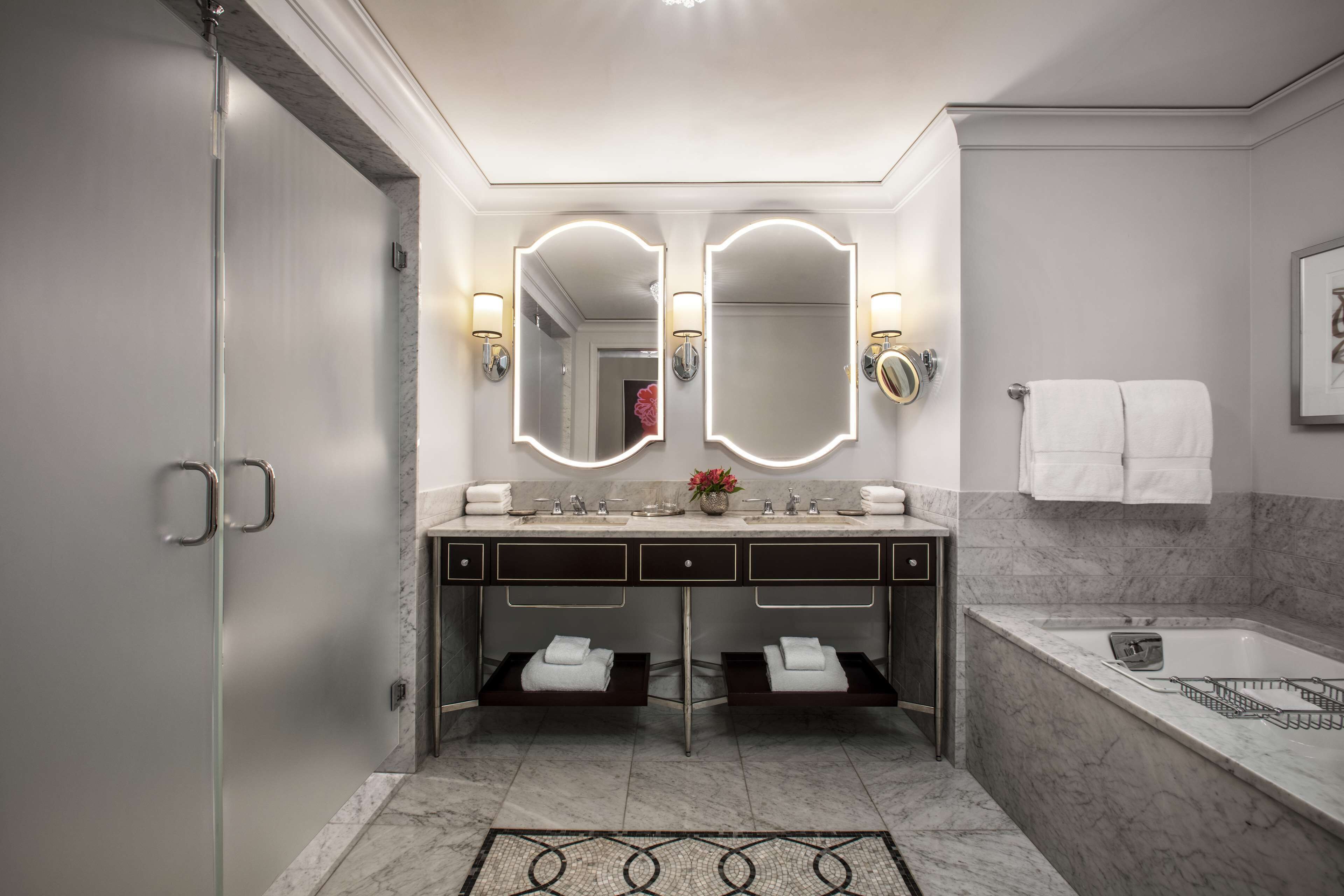 A modern bathroom with a double vanity, two mirrors, and a bathtub.