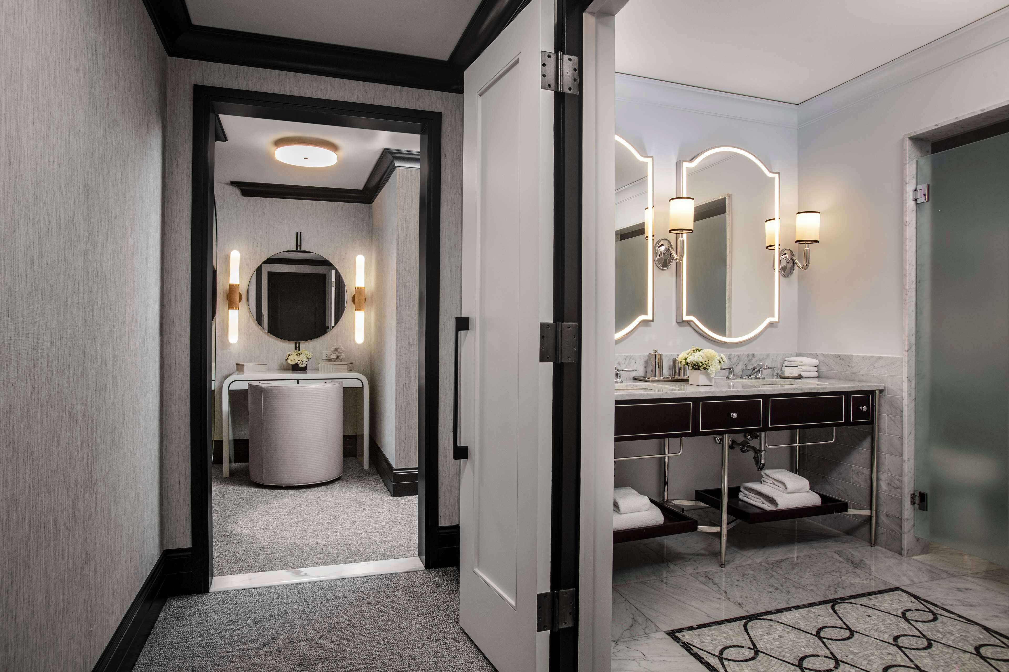 A modern bathroom with a round sink, two wall-mounted mirrors, and a vanity with a marble countertop.