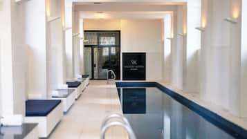 Un hall d’hôtel moderne doté d’un espace piscine, de coins salon et d’un comptoir d’accueil.