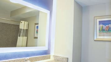 A bathroom with a granite countertop, a sink, and a mirror.