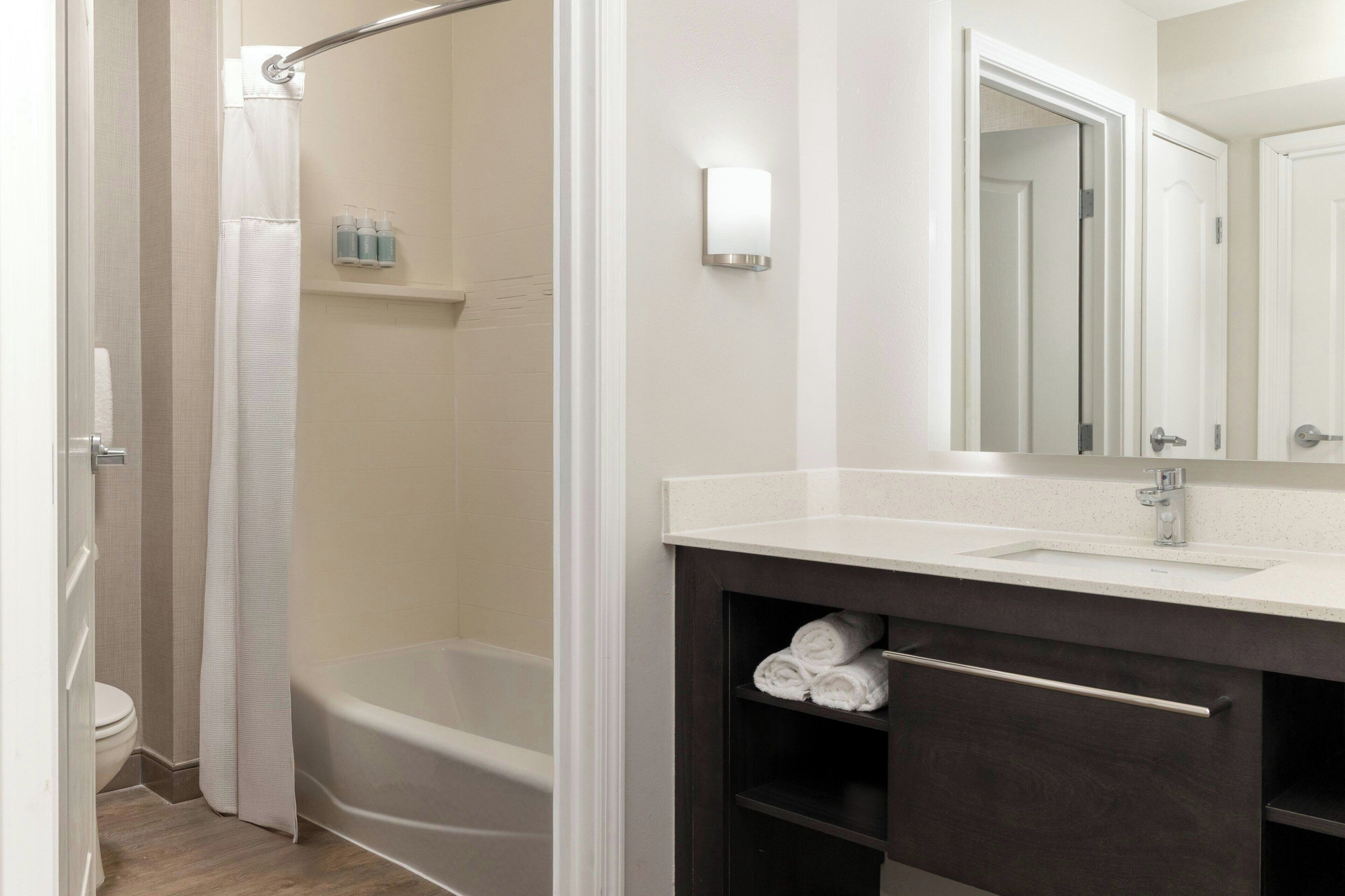 Une salle de bain moderne avec une baignoire, un meuble-lavabo avec un miroir et un rideau de douche.