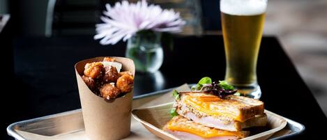 A tray with a sandwich, a glass of beer, and a paper cup of chicken wings.