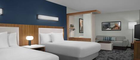 A hotel room with two beds, a sofa, a TV, a lamp, and a painting on the wall.
