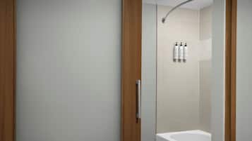 Un baño moderno con bañera, zona de ducha y puerta de madera.