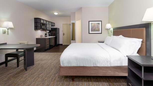 A hotel room with a bed, a desk, a chair, a kitchenette, and a framed picture on the wall. - Candlewood Suites Athens by IHG (Athens)
