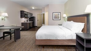A hotel room with a bed, a desk, a chair, a kitchenette, and a framed picture on the wall. - Candlewood Suites Athens by IHG (Athens)