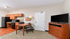 A compact hotel room with a kitchenette, a dining area, a TV, and a door. - Candlewood Suites Athens by IHG (Athens)
