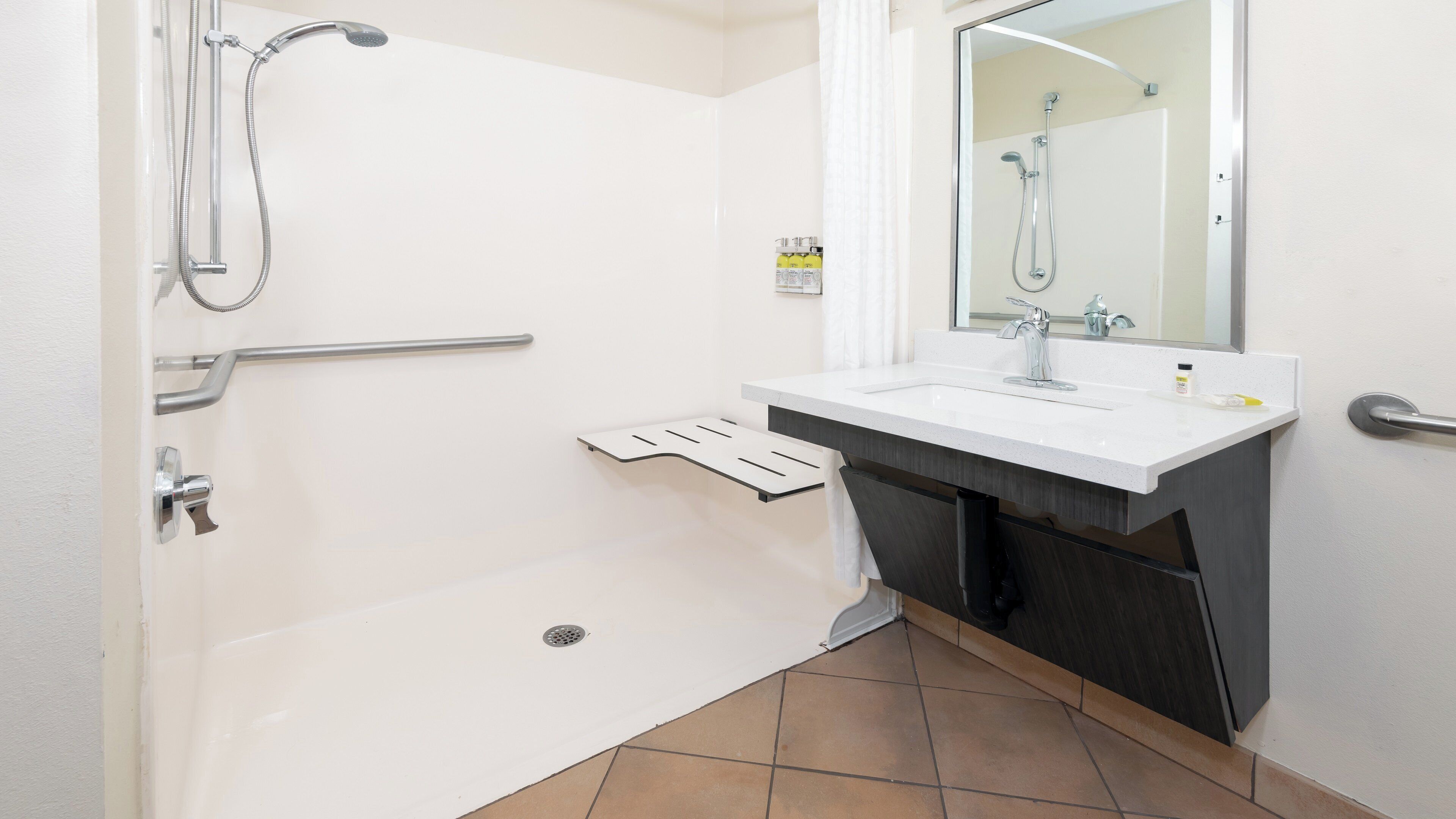 Un baño moderno con bañera, ducha, lavabo con espejo y perchero para toallas.