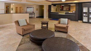 A lobby with two sofas and three ottomans, a reception desk, and a bulletin board. - Candlewood Suites Athens by IHG (Athens)